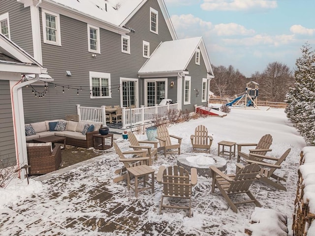 snow covered rear of property with an outdoor living space with a fire pit and a playground