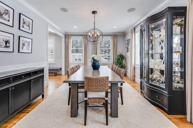 dining space with ornamental molding, an inviting chandelier, and light hardwood / wood-style floors