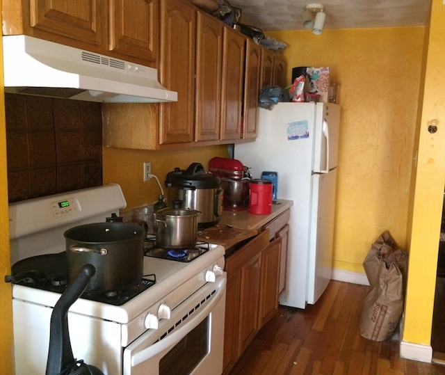 kitchen with white appliances and dark hardwood / wood-style floors