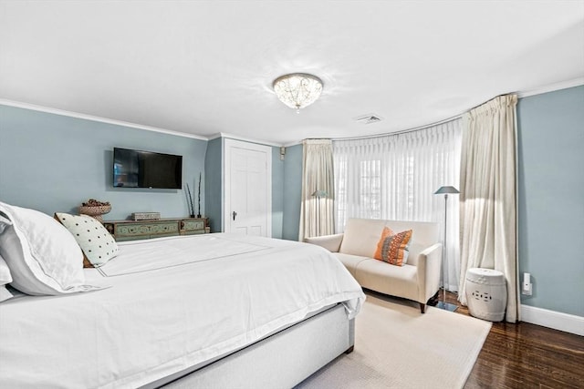 bedroom featuring ornamental molding, visible vents, baseboards, and wood finished floors