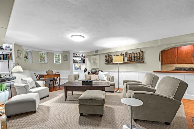 living room featuring light wood-style floors, visible vents, and a textured ceiling