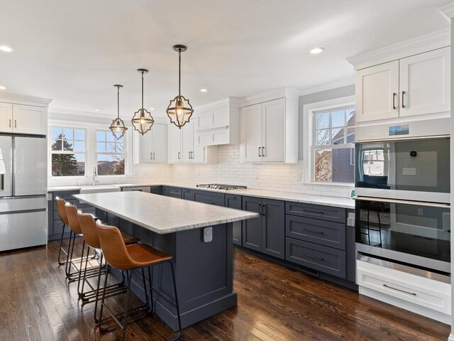 kitchen featuring appliances with stainless steel finishes, light countertops, backsplash, gray cabinetry, and ornamental molding