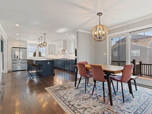 dining space with crown molding, recessed lighting, a notable chandelier, and dark wood finished floors