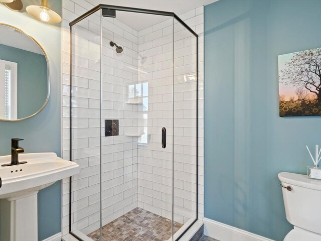 full bathroom with toilet, a sink, and a stall shower