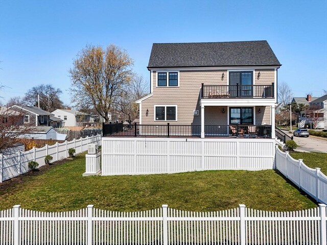 rear view of house with a lawn, a fenced backyard, a balcony, and a shingled roof