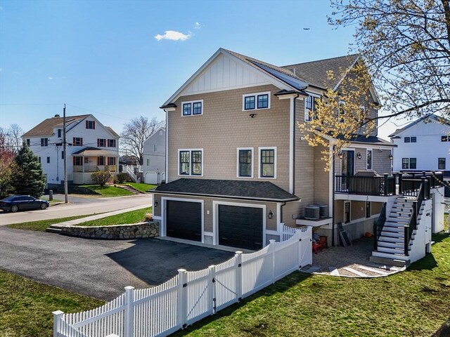 rear view of property with a residential view, fence private yard, a garage, stairway, and aphalt driveway