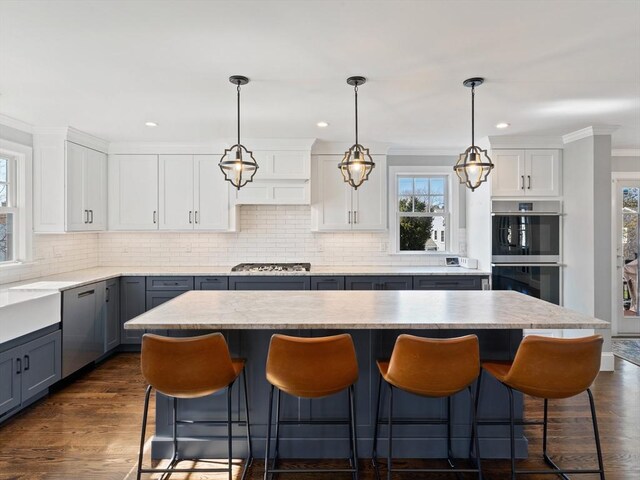 kitchen with appliances with stainless steel finishes, a breakfast bar, gray cabinets, and tasteful backsplash