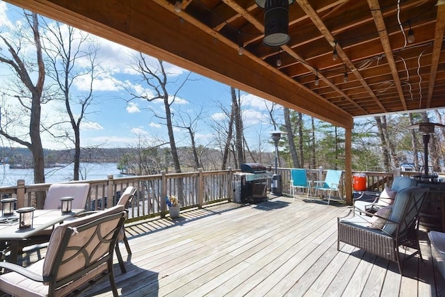 wooden deck with grilling area, a water view, and ceiling fan