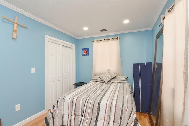 bedroom featuring a closet, crown molding, baseboards, wood finished floors, and recessed lighting