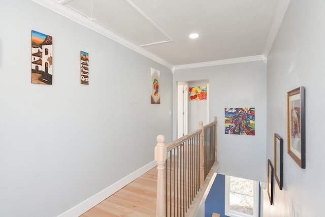 hallway with attic access, baseboards, crown molding, and an upstairs landing