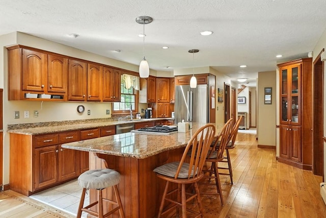 105 Old Barn Path, Marshfield, MA 02050 - kitchen with appliances with stainless steel finishes, a sink, brown cabinets, a breakfast bar area, and recessed lighting
