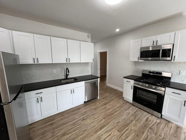 110 Old Harbor St, Boston, MA 02127 - kitchen with appliances with stainless steel finishes, a sink, decorative backsplash, light wood-style flooring, and white cabinets