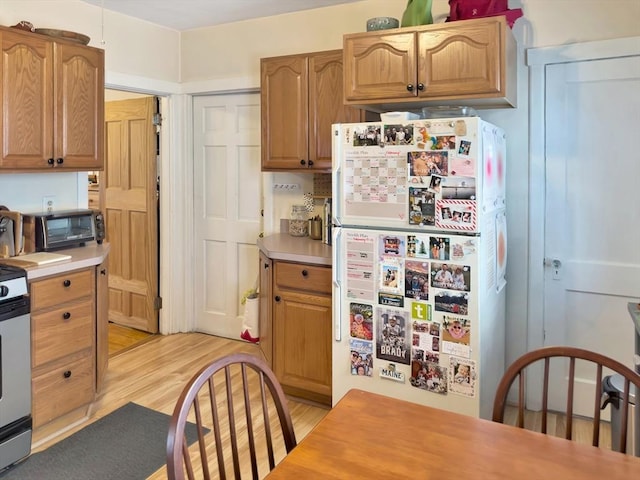 kitchen featuring light countertops, light wood-type flooring, range, and freestanding refrigerator