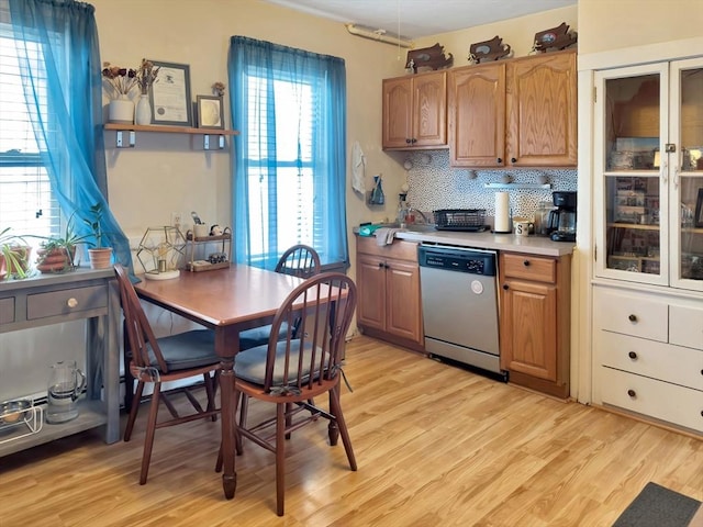 kitchen with decorative backsplash, light countertops, light wood finished floors, and stainless steel dishwasher