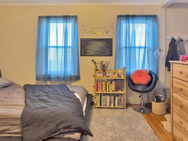 bedroom with ornamental molding and wood finished floors