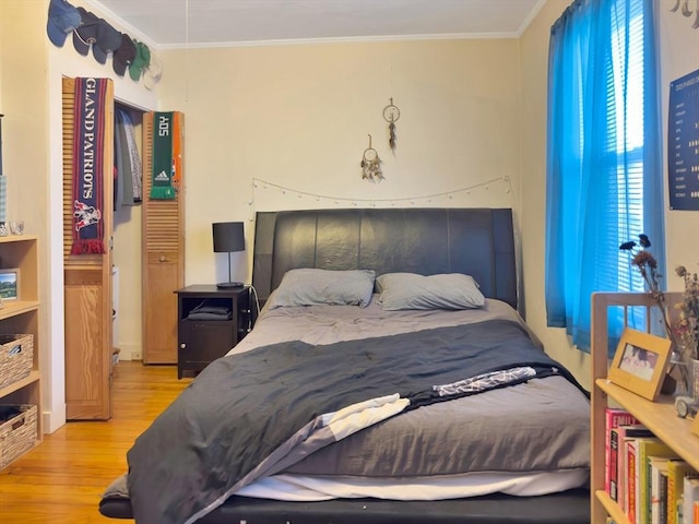 bedroom with crown molding and wood finished floors