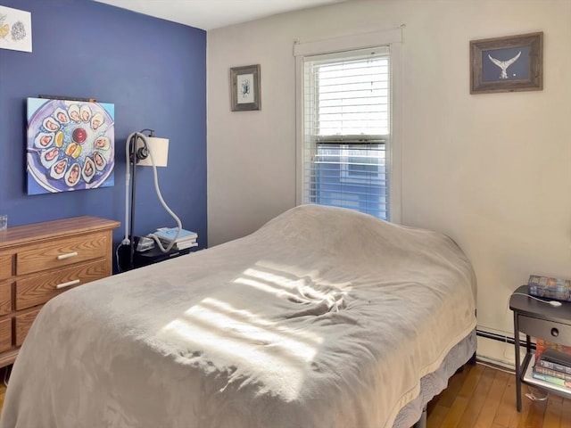 bedroom with a baseboard radiator and wood finished floors