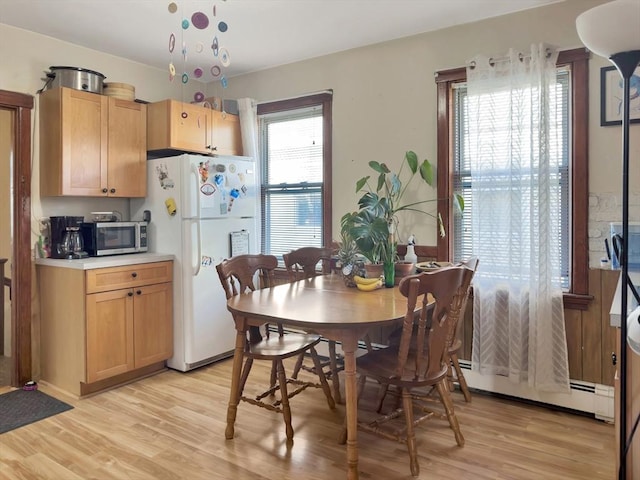 dining space featuring a baseboard radiator and light wood-style floors