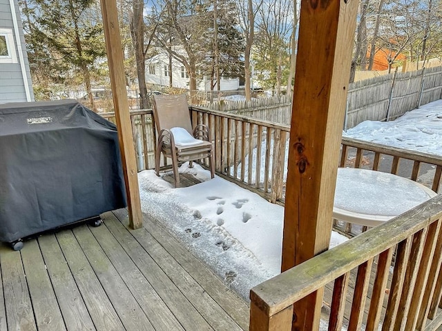 snow covered deck featuring grilling area and fence