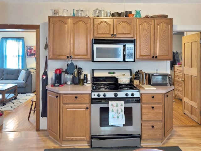 kitchen featuring light wood-type flooring, a toaster, appliances with stainless steel finishes, and light countertops