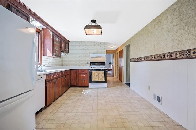 kitchen with a sink, ventilation hood, white appliances, light countertops, and visible vents