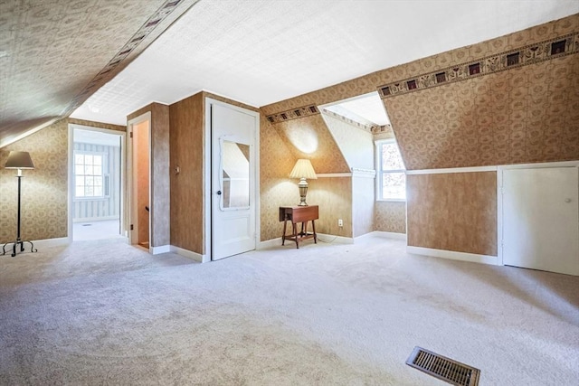 bonus room with carpet floors, vaulted ceiling, wallpapered walls, and visible vents