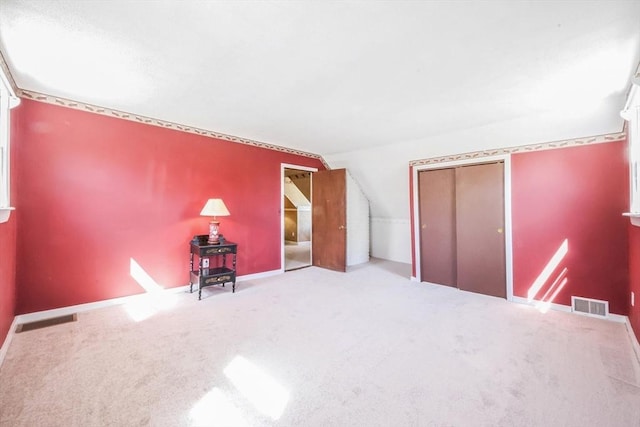 additional living space with carpet floors, baseboards, lofted ceiling, and visible vents