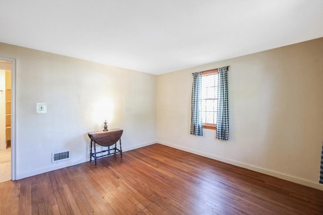 spare room with baseboards, hardwood / wood-style flooring, and visible vents