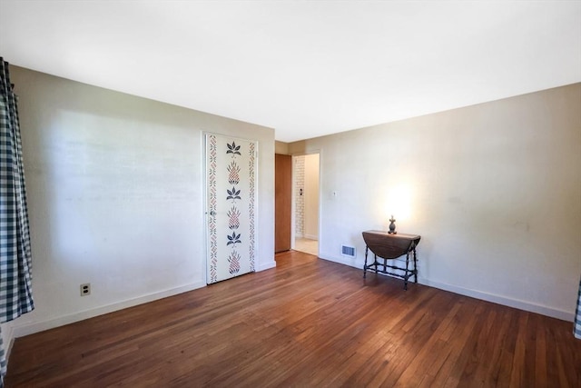 unfurnished room featuring wood-type flooring, baseboards, and visible vents
