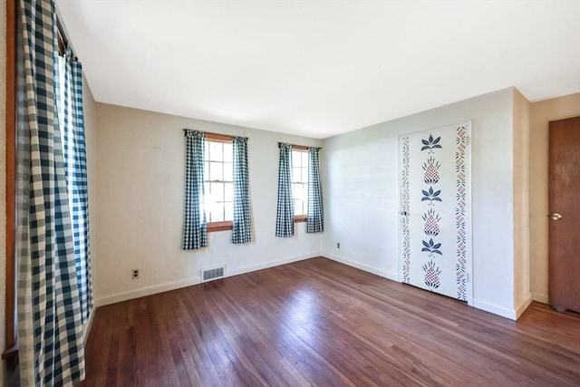 empty room featuring visible vents, baseboards, and wood finished floors