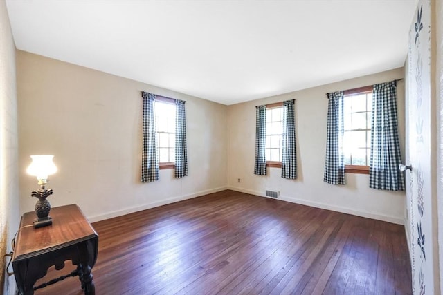 spare room with a healthy amount of sunlight, baseboards, hardwood / wood-style flooring, and visible vents