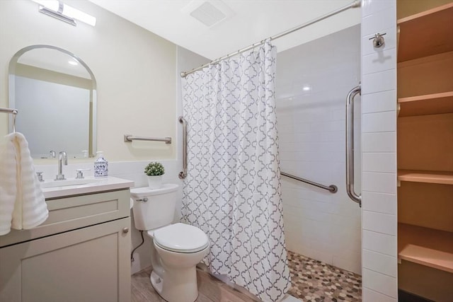 full bathroom featuring vanity, a tile shower, toilet, and visible vents