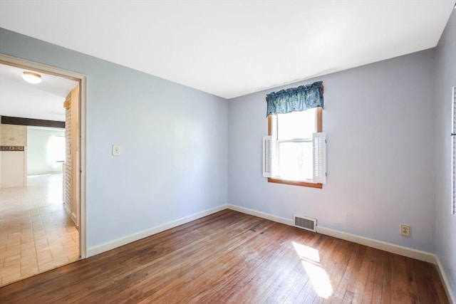 unfurnished room with baseboards, wood-type flooring, and visible vents