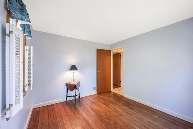 unfurnished room featuring baseboards and hardwood / wood-style flooring
