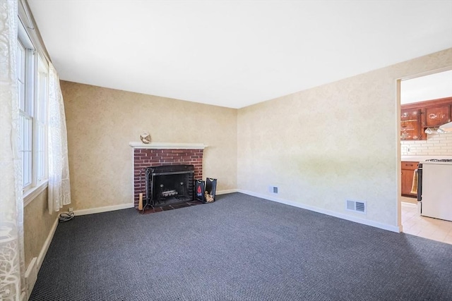 unfurnished living room featuring carpet floors, a wealth of natural light, a fireplace, and visible vents