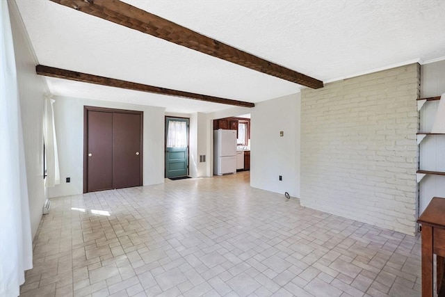 unfurnished living room with beamed ceiling, brick patterned floor, a textured ceiling, and visible vents