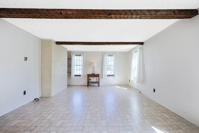 spare room featuring a textured ceiling, visible vents, and beam ceiling