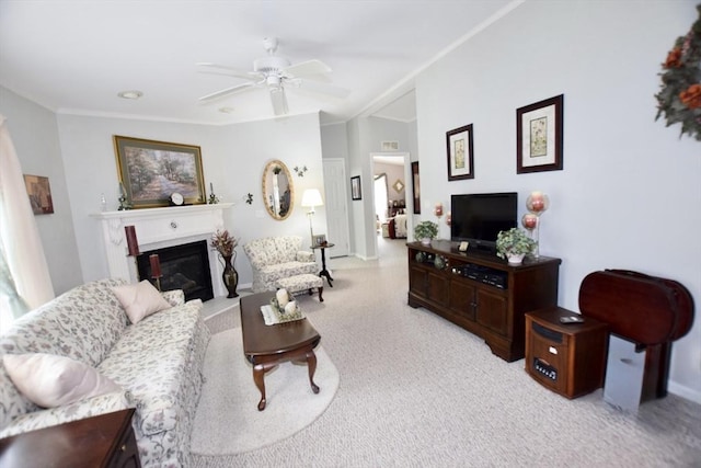 living area featuring ornamental molding, ceiling fan, carpet floors, and a glass covered fireplace