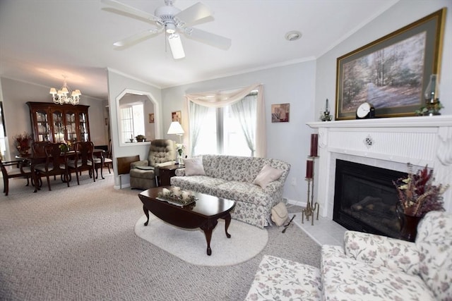 carpeted living room featuring a glass covered fireplace, ornamental molding, and ceiling fan with notable chandelier