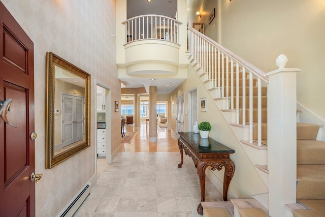 foyer with baseboard heating and a towering ceiling