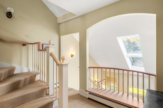 staircase with a skylight, high vaulted ceiling, carpet, and a baseboard radiator