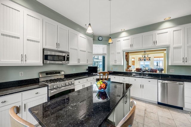 kitchen featuring decorative light fixtures, stainless steel appliances, a healthy amount of sunlight, and dark stone countertops