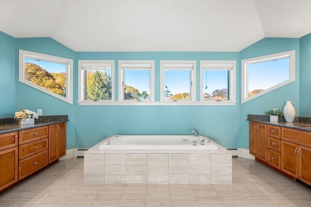 bathroom with vanity, a relaxing tiled tub, lofted ceiling, and tile patterned floors