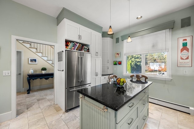 kitchen with a baseboard radiator, a kitchen island, high quality fridge, white cabinets, and dark stone countertops