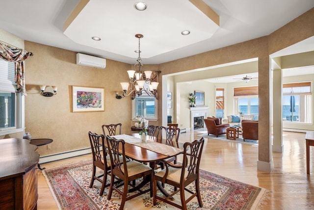 dining room featuring a wall unit AC, light hardwood / wood-style flooring, baseboard heating, and ceiling fan with notable chandelier