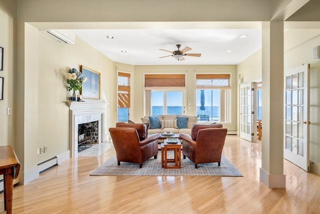 living room with ceiling fan, a high end fireplace, light wood-type flooring, a wall mounted air conditioner, and a water view