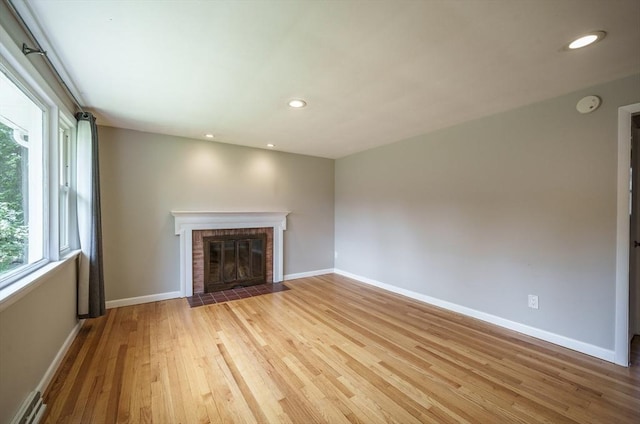 226 Dutchess St, Springfield, MA 01129 - unfurnished living room with baseboard heating, light wood-type flooring, baseboards, a brick fireplace, and recessed lighting