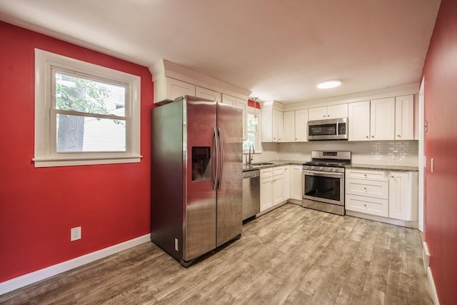 226 Dutchess St, Springfield, MA 01129 - kitchen featuring appliances with stainless steel finishes, a sink, light wood-style flooring, white cabinets, and tasteful backsplash