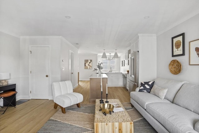 living room featuring sink, crown molding, and light hardwood / wood-style floors