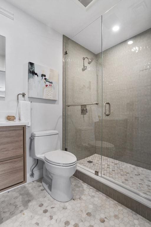 bathroom with a shower with shower door, toilet, vanity, and tile patterned flooring